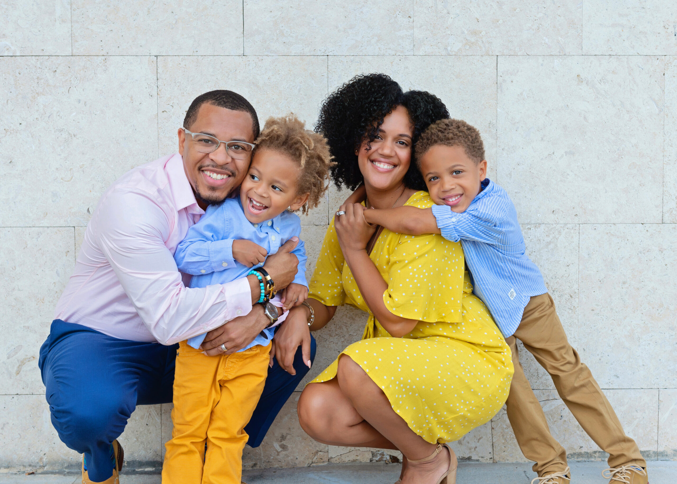 A joyful family portrait with parents hugging their two young sons.