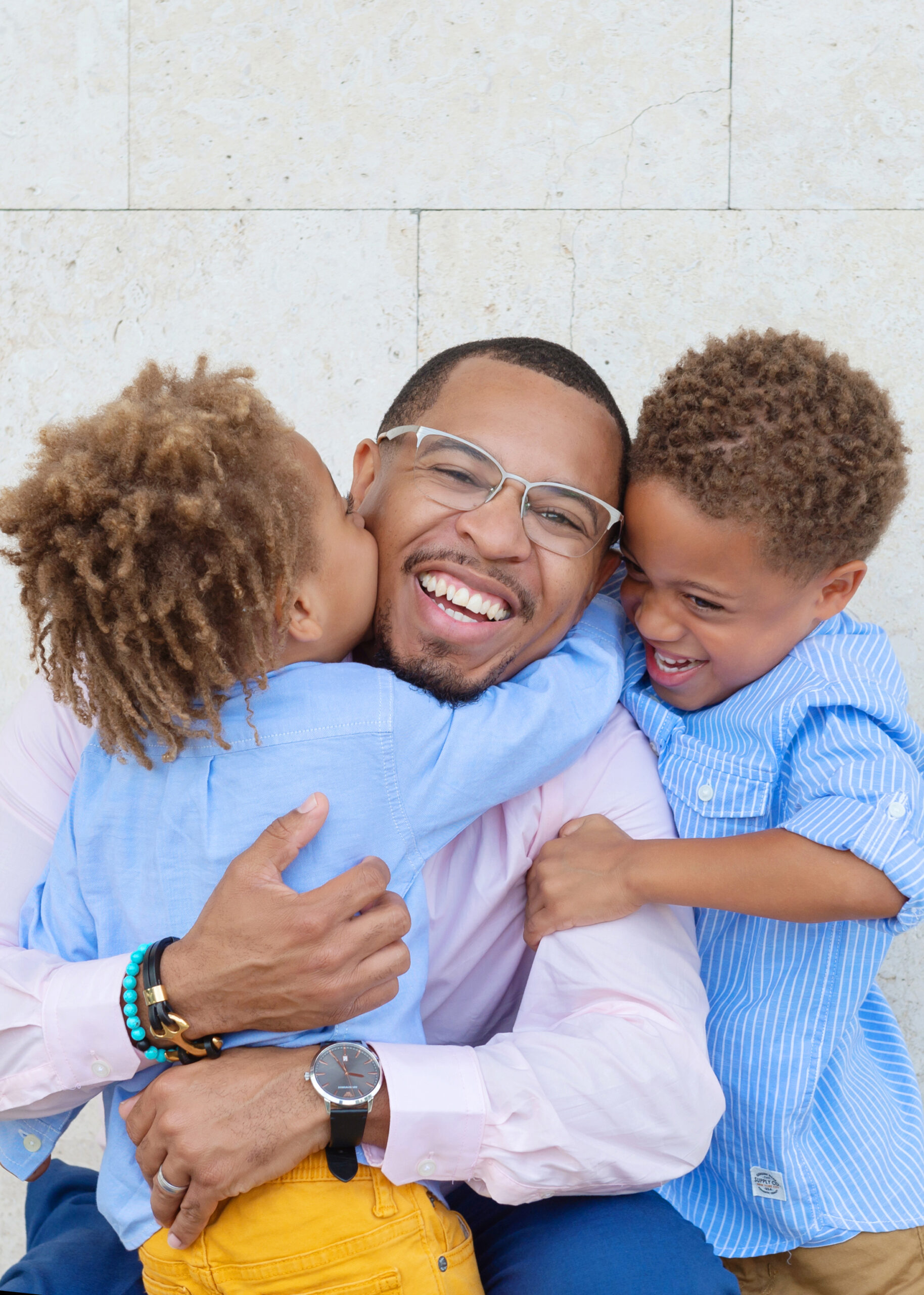 A father receiving hugs from his two sons during a joyful photo session.