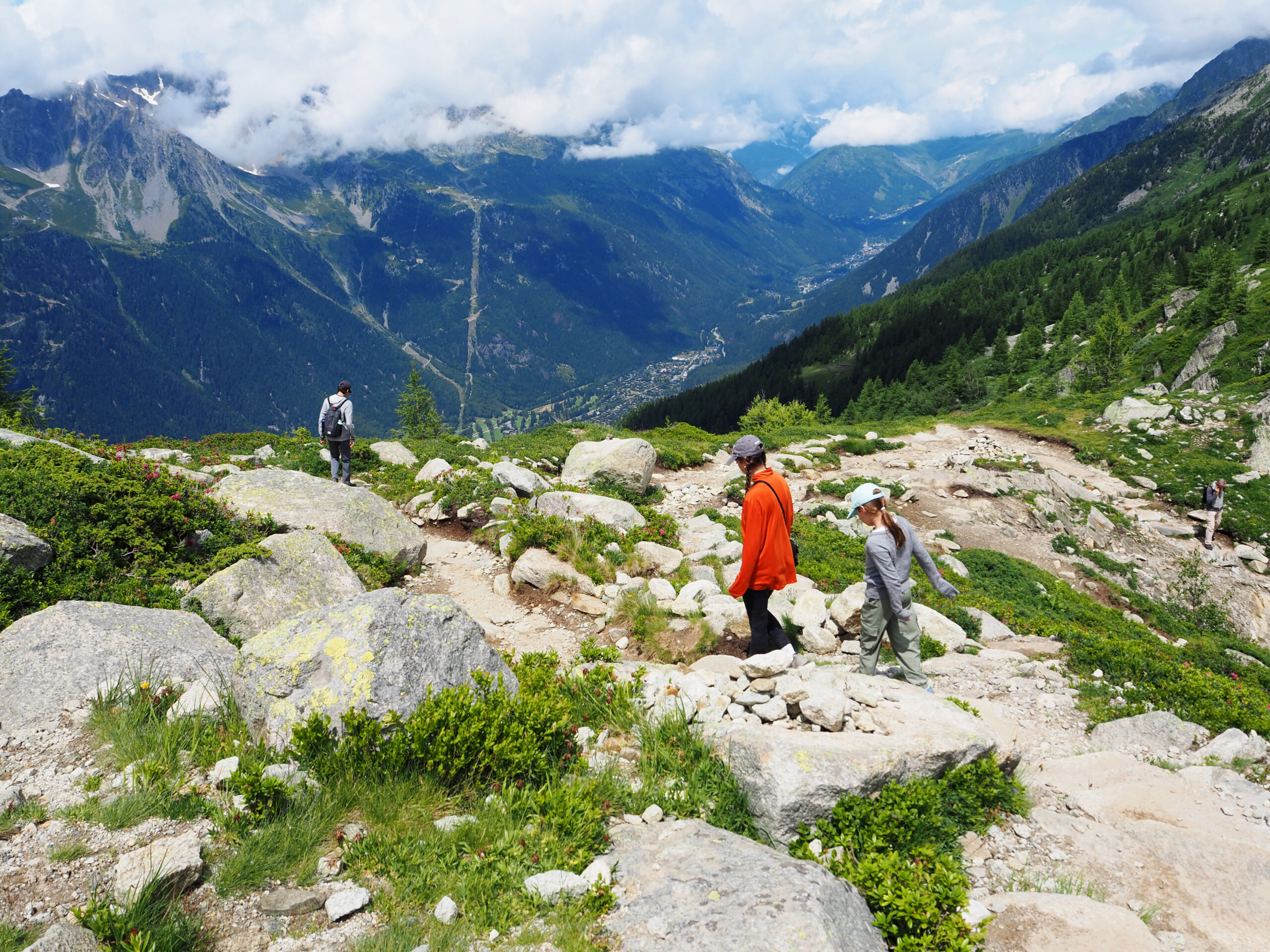 People hiking along rocky terrain in the French Alps with a panoramic view of the mountains